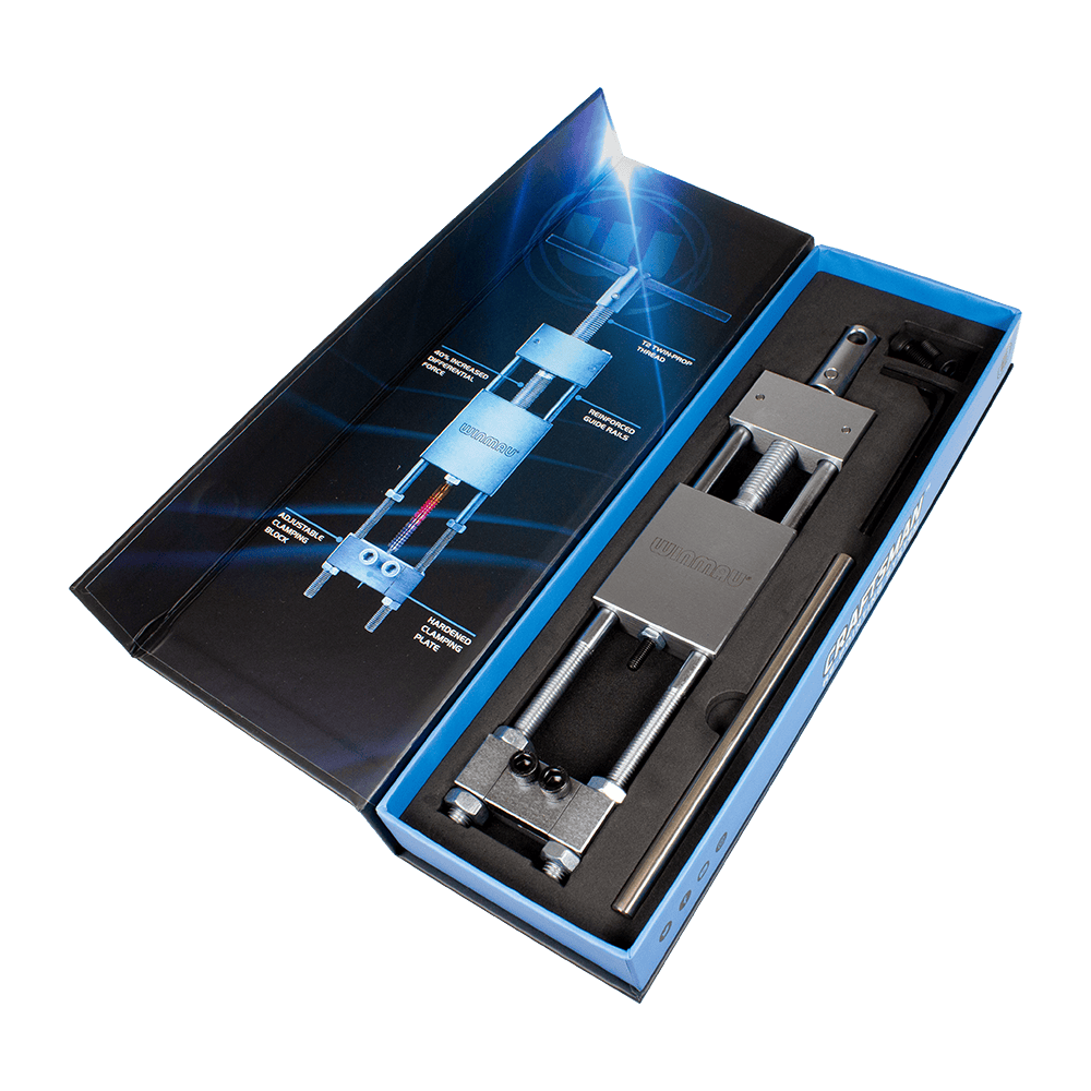 8425-Winmau-Craftsman-Re-pointing-System-5Rw3CTvWlDH1nL Das Bild zeigt das Produkt "Winmau Craftsman Re-Pointing System Spitzenwechsler" in einer geöffneten Verpackung. Das Werkzeug liegt ordentlich in einer Schaumstoffeinlage, daneben ist eine grafische Anleitung zu sehen.