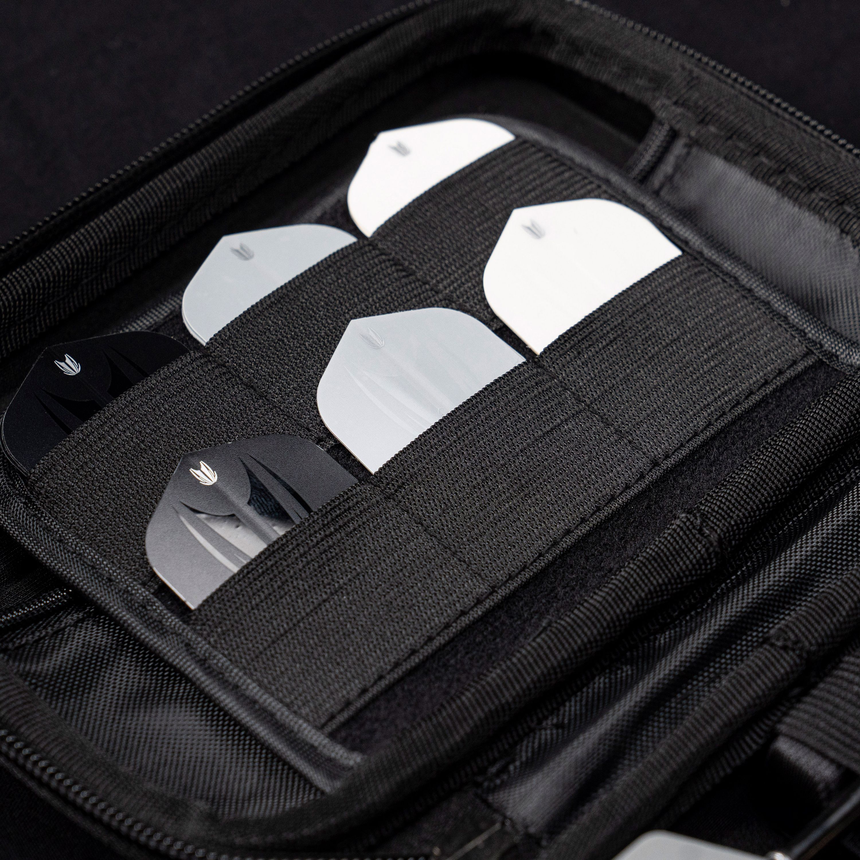 Estuche para dardos Takoma Ghost Series de Stephen Bunting Das Bild zeigt das Target Takoma Bolide Dartcase, in dem mehrere Dart-Flights ordentlich in elastischen Halterungen verstaut sind. Das Case ist schwarz und bietet sicheren Schutz für das Dartzubehör.