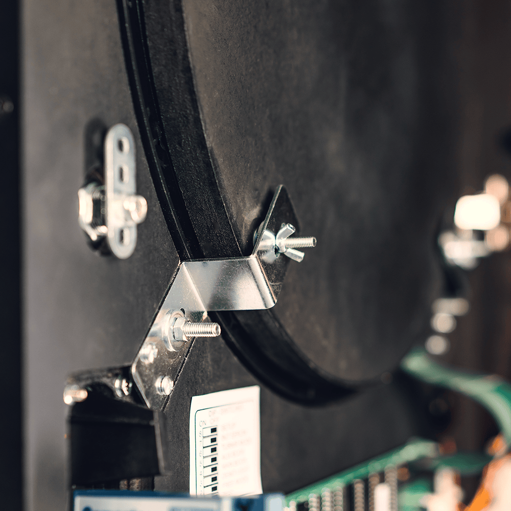 Karella_E-Master_Dartautomat_Detail_Innenansicht_A Das Bild zeigt einen Nahaufnahmebereich des Karella E-MASTER Dartautomaten mit Münzeinwurf. Zu sehen sind Metallbefestigungen, Schrauben und ein Teil der Elektronik im Inneren des Geräts.