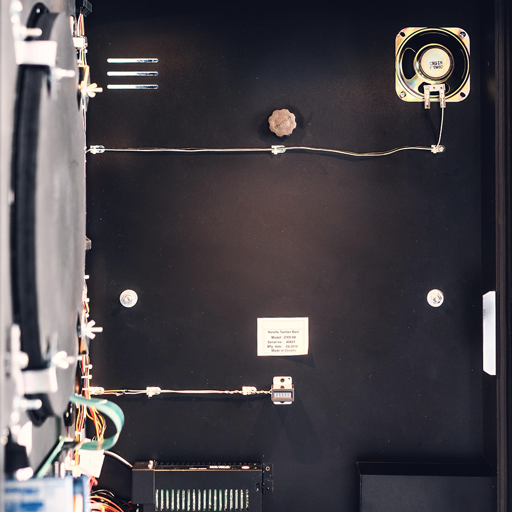 Karella_E-Master_Dartautomat_Detail_Innenansicht_BEGHZXvfOMzklR Das Bild zeigt das geöffnete Innere eines Karella E-MASTER Dartautomaten ohne Münzeinwurf. Verschiedene elektronische Komponenten und Kabel sind an der Innenwand sichtbar.