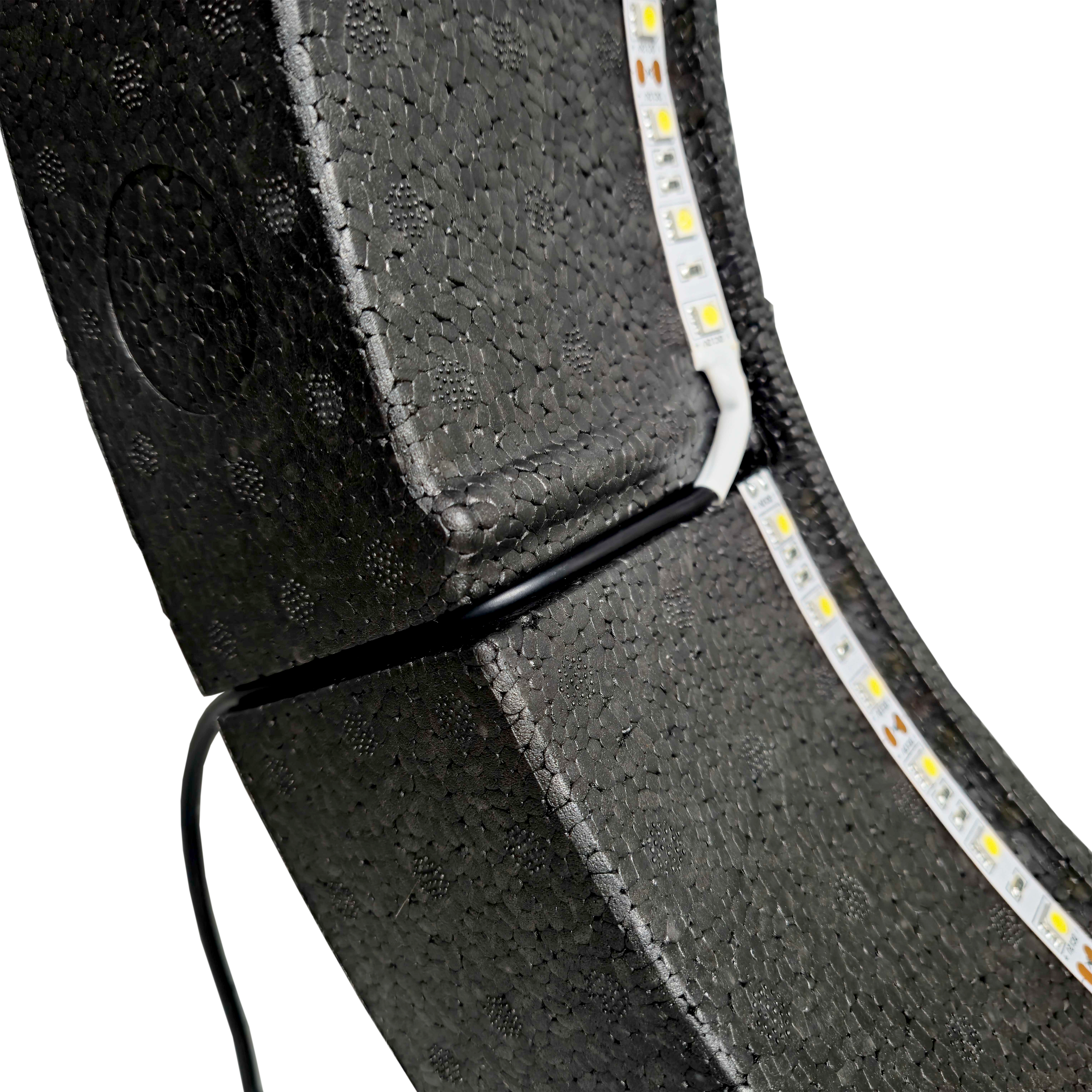 Sistema de iluminación envolvente Lumo Light de Bulls NL Das Bild zeigt das „Bulls NL Lumo Light Surround Beleuchtungssystem“ mit LED-Leuchtstreifen auf einer schwarzen, strukturierten Oberfläche. Ein Kabel ist ebenfalls an das Beleuchtungssystem angeschlossen.