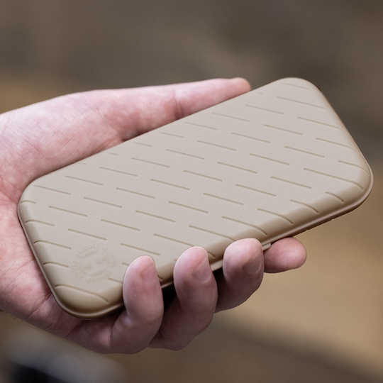 Estuche para dardos Harrows Slimcase Eine Hand hält ein schlankes, steingraues Etui mit einem dezenten Muster. Das Etui wirkt stabil und ist wahrscheinlich für Dartzubehör gedacht.