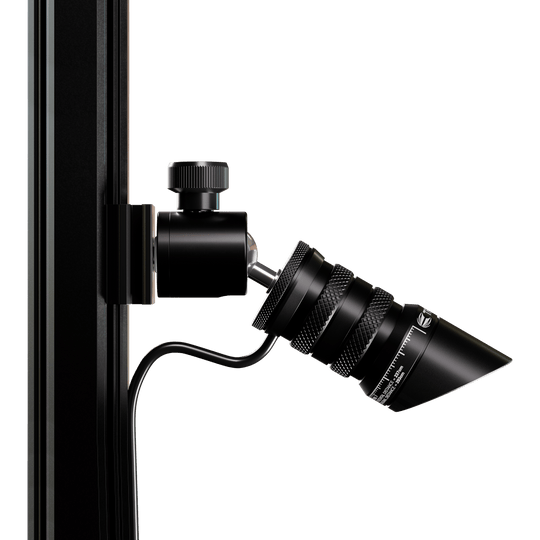 Láser de objetivo MOD Oche Das Bild zeigt das Produkt "Target MOD Laser Oche", das an einer vertikalen Stange befestigt ist. Es handelt sich um ein schwarzes, zylindrisches Gerät mit einem Kabelanschluss und feinen Details.