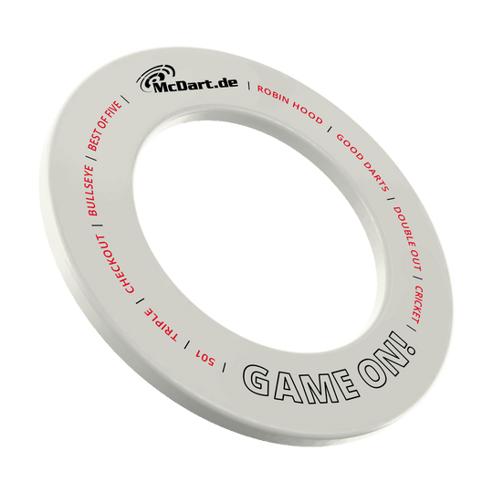 Juego de dardos McDart en la diana Das Bild zeigt einen weißen Dartboard-Surround-Ring mit der Aufschrift "McDart.de" und "GAME ON!". Auf dem Ring stehen außerdem in roter Schrift Begriffe rund um das Dartspiel wie "BULLSEYE", "TRIPLE", "CHECKOUT" und "CRICKET".