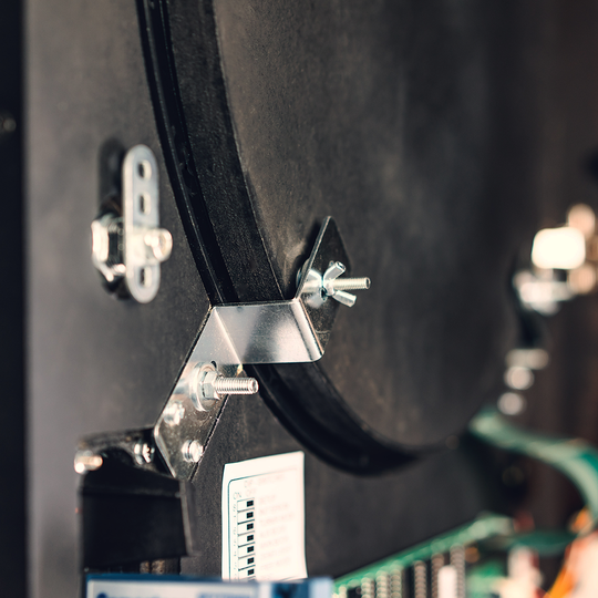 Karella_E-Master_Dartautomat_Detail_Innenansicht_A Das Bild zeigt einen Nahaufnahmebereich des Karella E-MASTER Dartautomaten mit Münzeinwurf. Zu sehen sind Metallbefestigungen, Schrauben und ein Teil der Elektronik im Inneren des Geräts.