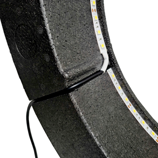 Sistema de iluminación envolvente Lumo Light de Bulls NL Das Bild zeigt das „Bulls NL Lumo Light Surround Beleuchtungssystem“ mit LED-Leuchtstreifen auf einer schwarzen, strukturierten Oberfläche. Ein Kabel ist ebenfalls an das Beleuchtungssystem angeschlossen.