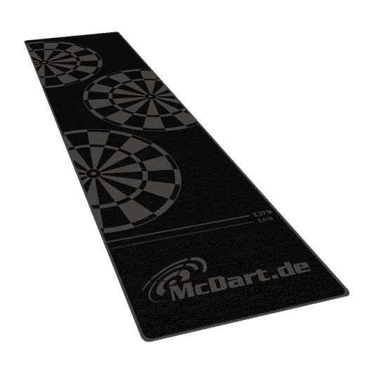 McDart Mono Dartteppich Auf dem Bild ist ein schwarzer Dartteppich mit Dartboard-Motiven zu sehen. Der Teppich trägt den Schriftzug „McDart.de“ und zeigt Abwurflinien für verschiedene Distanzen.